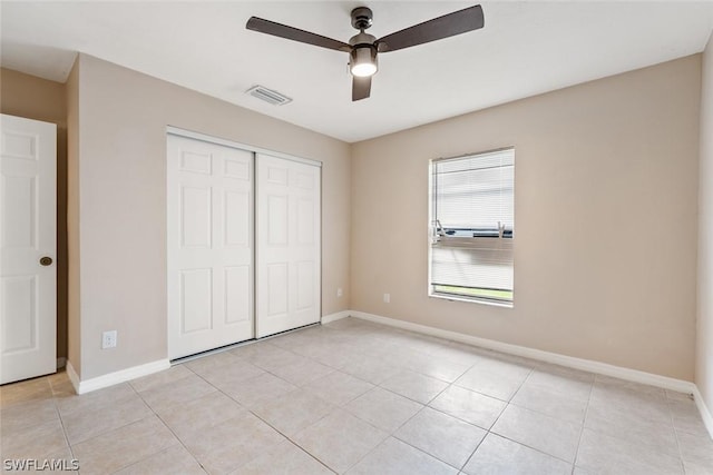 unfurnished bedroom with light tile patterned floors, ceiling fan, visible vents, baseboards, and a closet