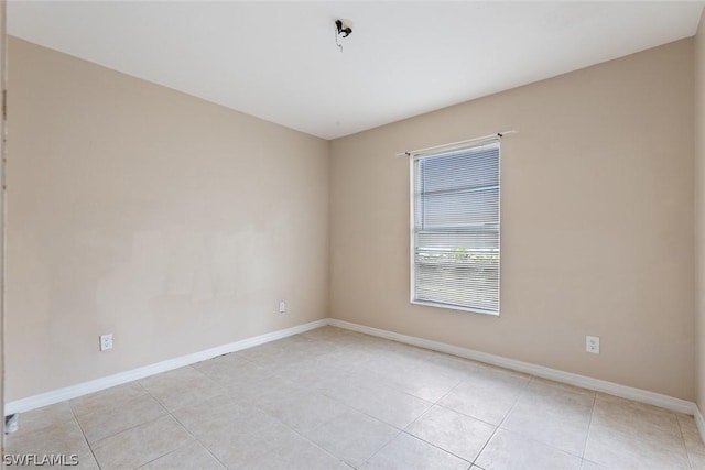 unfurnished room with light tile patterned flooring and baseboards