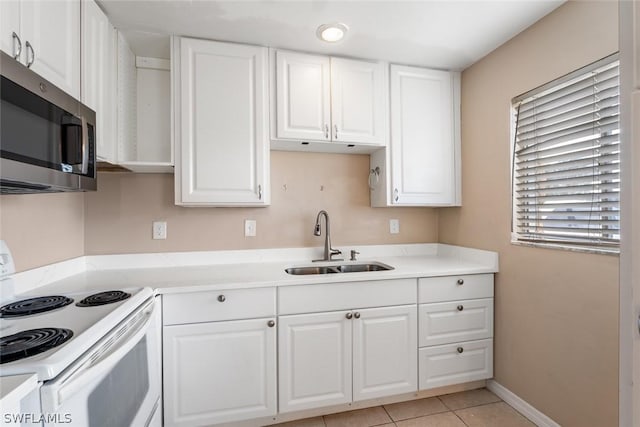 kitchen with light countertops, white range with electric stovetop, stainless steel microwave, and a sink