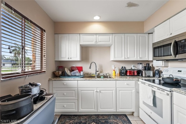 kitchen featuring white cabinetry, electric range, stainless steel microwave, and a sink