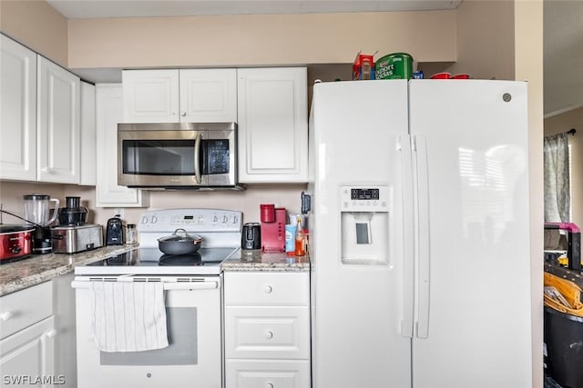 kitchen featuring white appliances, light stone countertops, and white cabinets