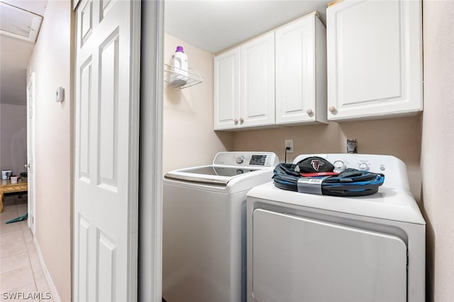 laundry area featuring washing machine and dryer, cabinet space, and light tile patterned floors