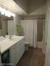 full bathroom with shower / bath combo with shower curtain, toilet, and vanity