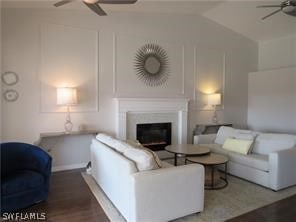 living room with hardwood / wood-style floors, ceiling fan, and vaulted ceiling