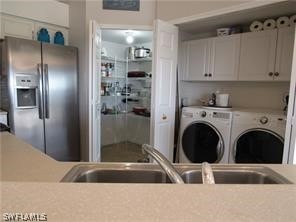 clothes washing area with sink, separate washer and dryer, and cabinets