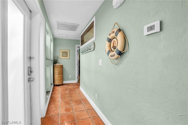 hallway featuring baseboards, visible vents, attic access, and light tile patterned flooring