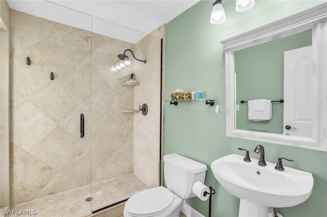 bathroom featuring a sink, toilet, and a stall shower