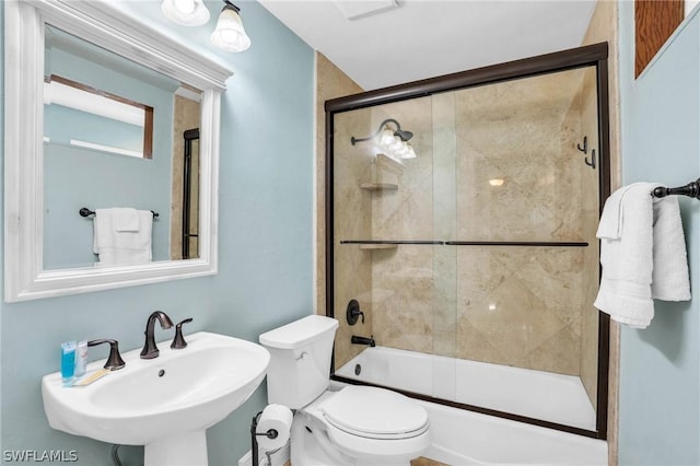 full bathroom featuring a sink, combined bath / shower with glass door, and toilet