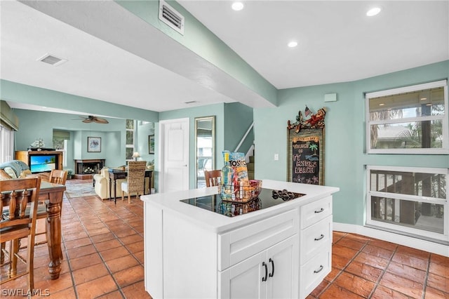 kitchen featuring black electric stovetop, white cabinets, tile patterned floors, ceiling fan, and a kitchen island