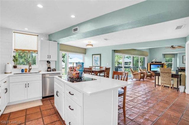 kitchen featuring a sink, visible vents, a breakfast bar area, dishwasher, and black stovetop