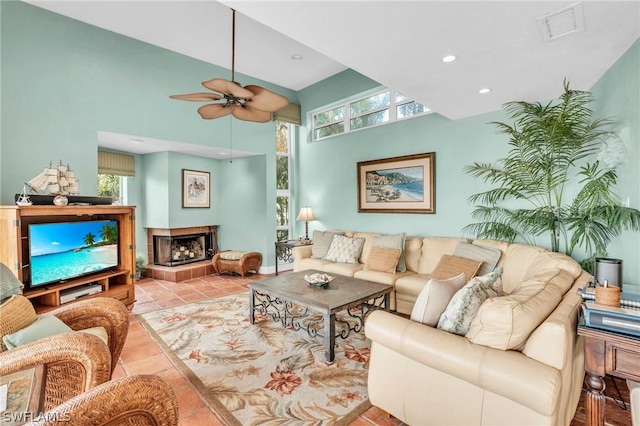 tiled living room with recessed lighting, ceiling fan, visible vents, a towering ceiling, and a fireplace