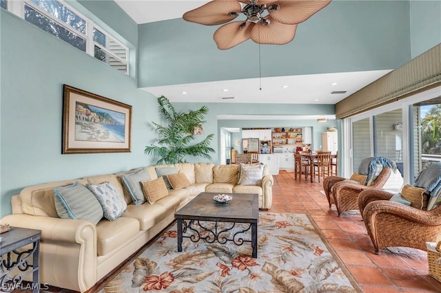 living room featuring ceiling fan, a high ceiling, and recessed lighting