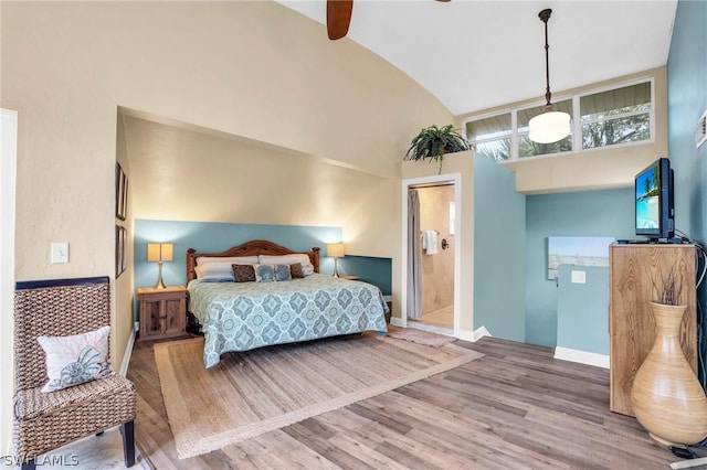 bedroom featuring hardwood / wood-style floors, ceiling fan, connected bathroom, and vaulted ceiling