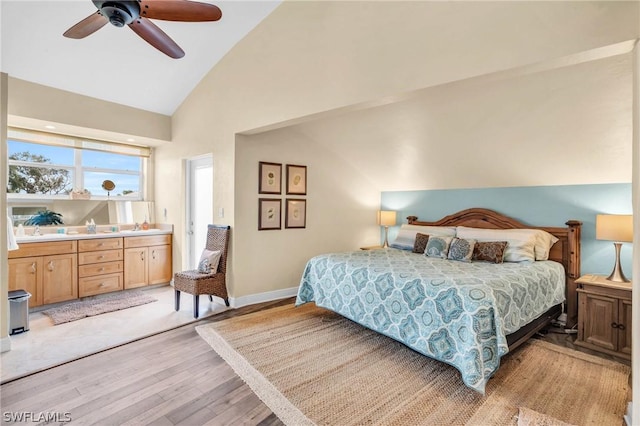 bedroom with baseboards, light wood finished floors, ceiling fan, a sink, and high vaulted ceiling