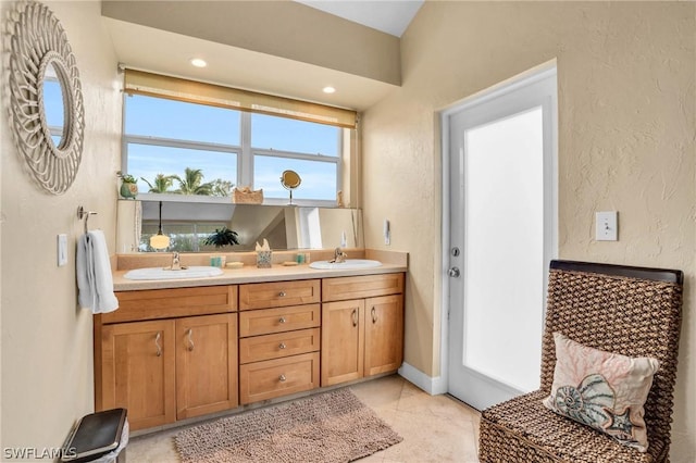 bathroom featuring tile patterned floors, double vanity, a sink, and a textured wall