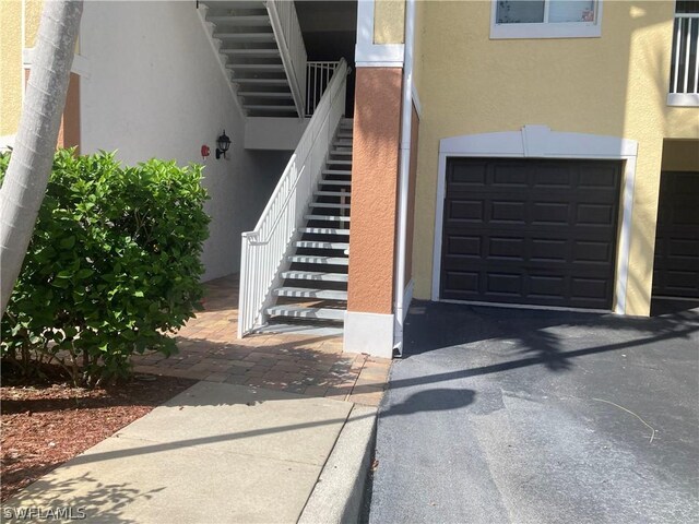 doorway to property featuring driveway, a garage, and stucco siding