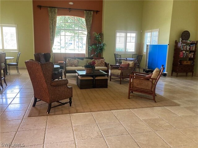 living room with stone tile flooring, plenty of natural light, and a towering ceiling