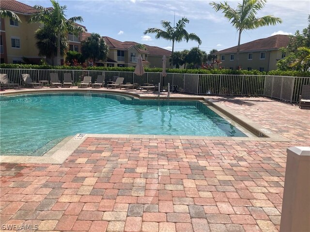 pool with a residential view, fence, and a patio