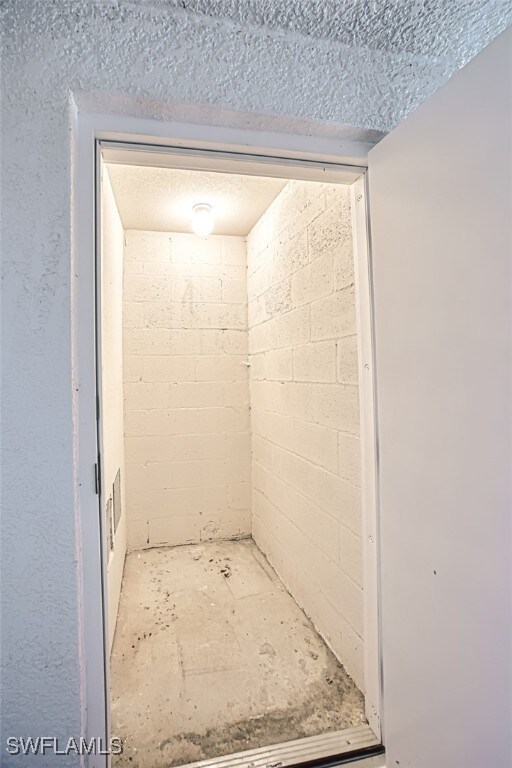 bathroom with concrete block wall and a textured ceiling