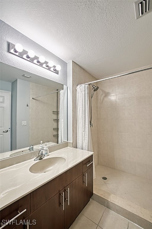 full bath with visible vents, tiled shower, a textured ceiling, and tile patterned floors