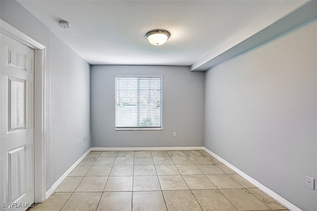 unfurnished room with a textured ceiling, baseboards, and light tile patterned floors