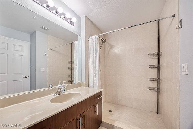 bathroom with a stall shower, visible vents, vanity, and a textured ceiling