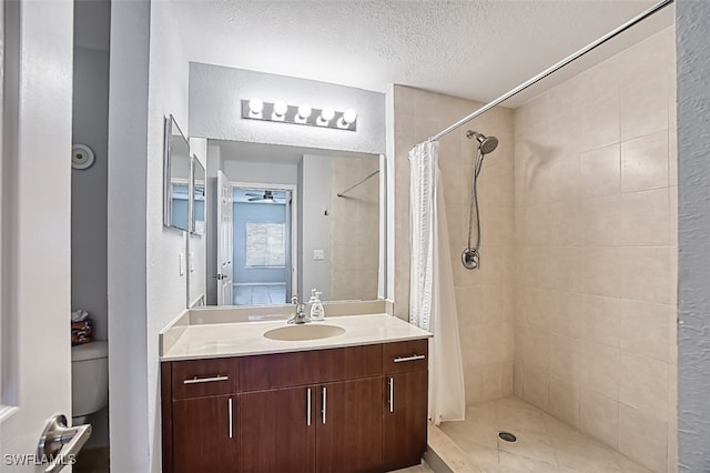 bathroom with a textured ceiling, a textured wall, toilet, vanity, and a stall shower