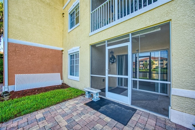 view of exterior entry with a patio and stucco siding