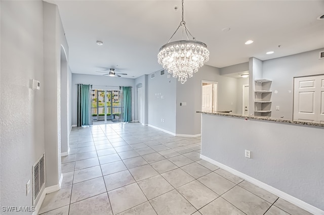 spare room with light tile patterned floors, visible vents, baseboards, and ceiling fan with notable chandelier