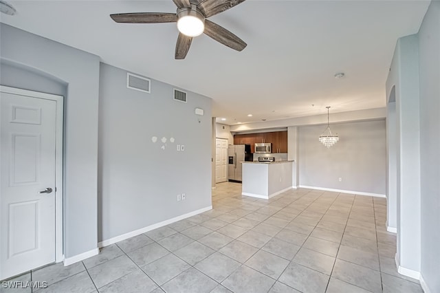 unfurnished living room with ceiling fan with notable chandelier, light tile patterned flooring, visible vents, and baseboards