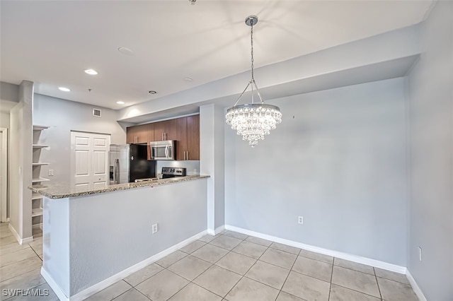 kitchen featuring pendant lighting, appliances with stainless steel finishes, brown cabinetry, light stone countertops, and a peninsula