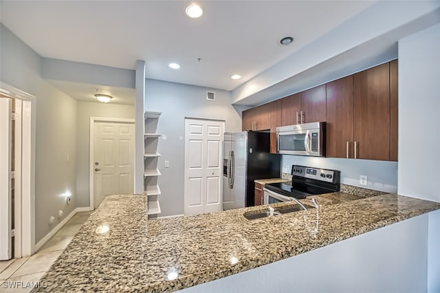 kitchen with stainless steel appliances, kitchen peninsula, light tile patterned floors, and stone countertops