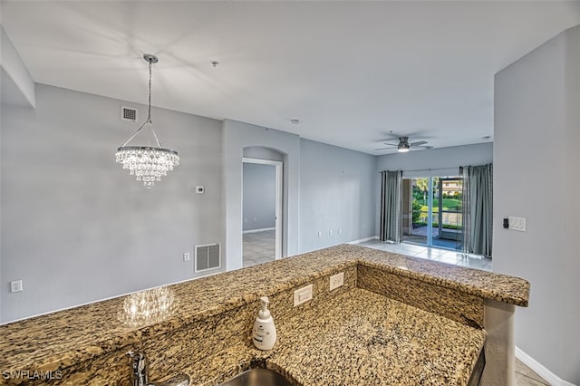 kitchen with hanging light fixtures and ceiling fan with notable chandelier