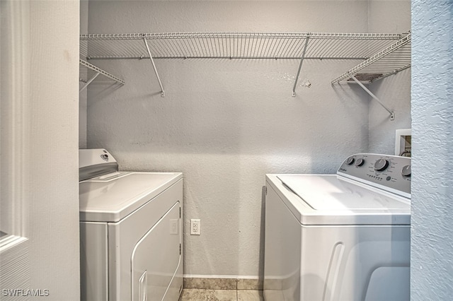 laundry room featuring a textured wall, light tile patterned flooring, independent washer and dryer, and baseboards