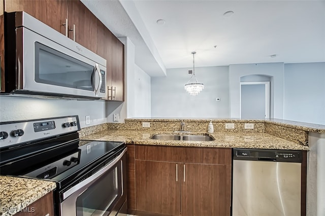 kitchen featuring stainless steel appliances, sink, hanging light fixtures, kitchen peninsula, and a notable chandelier