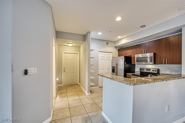 kitchen featuring kitchen peninsula, stone counters, appliances with stainless steel finishes, and light tile patterned flooring