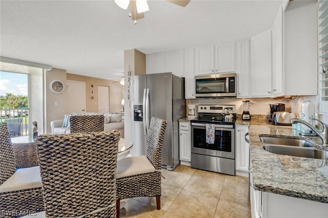 kitchen featuring white cabinets, stainless steel appliances, light stone counters, and sink