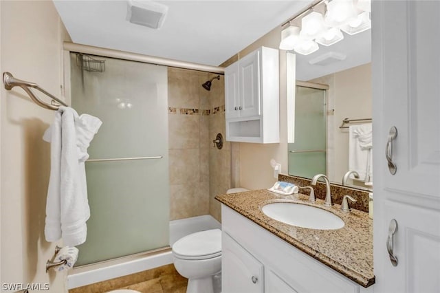 bathroom featuring toilet, vanity, and a shower with shower door