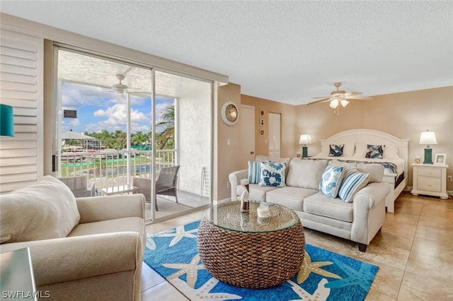 living room with light tile patterned flooring, ceiling fan, and a textured ceiling