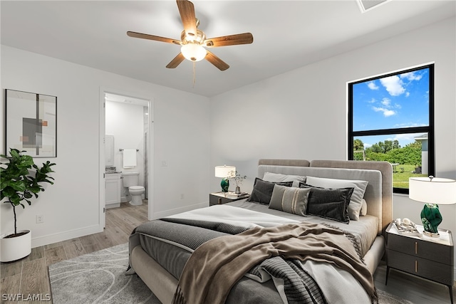 bedroom featuring ceiling fan, ensuite bath, and light hardwood / wood-style flooring