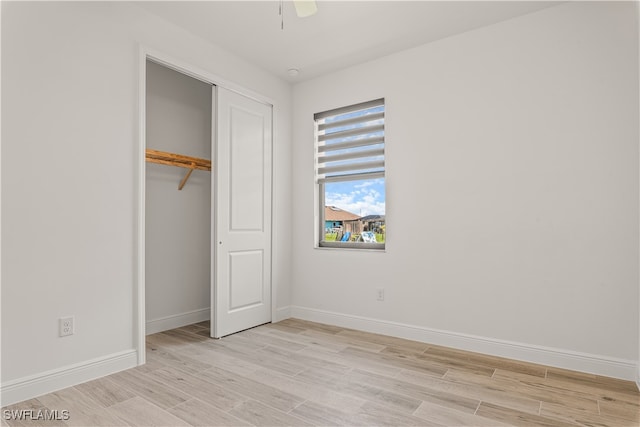 unfurnished bedroom featuring light hardwood / wood-style floors, a closet, and ceiling fan