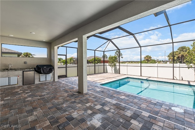 view of pool featuring glass enclosure, sink, an outdoor kitchen, a patio area, and area for grilling