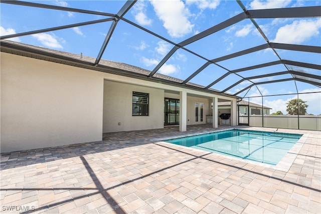 view of swimming pool with glass enclosure and a patio