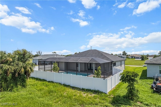 back of property featuring a fenced in pool, glass enclosure, and a lawn