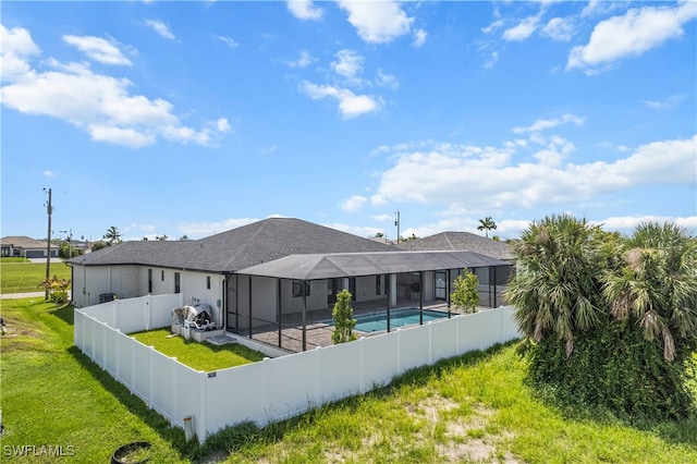 back of property featuring a lawn, glass enclosure, a patio area, and a fenced in pool