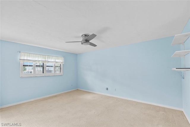 spare room with light carpet, a ceiling fan, and baseboards