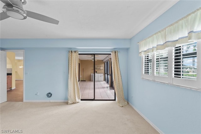 carpeted empty room featuring ceiling fan and baseboards