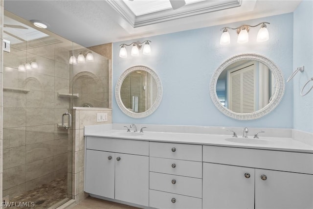 full bathroom with double vanity, a shower stall, crown molding, and a sink