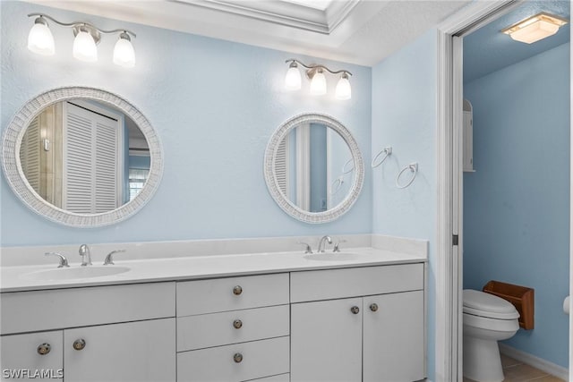 full bathroom with double vanity, a sink, and toilet