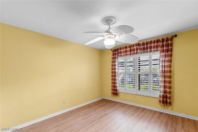 unfurnished room with ceiling fan, wood finished floors, and baseboards